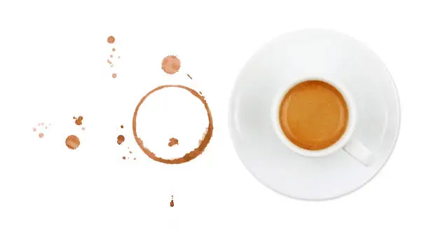 White cup full of espresso coffee on saucer, with brown circle coffee stains and drops isolated on white background, elevated top view, directly above