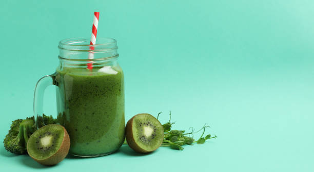 istock Mason jar with green smoothie and ingredients on mint background 1311123958
