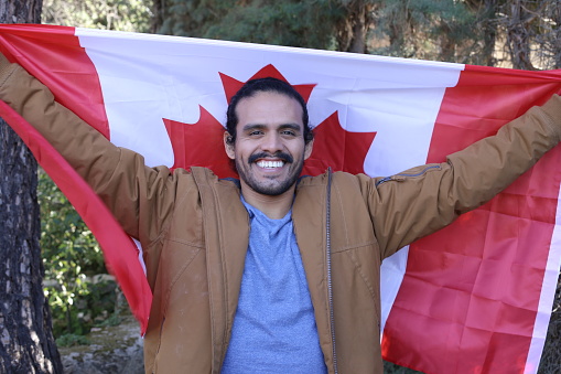 Proud ethnic man holding the Canadian flag.
