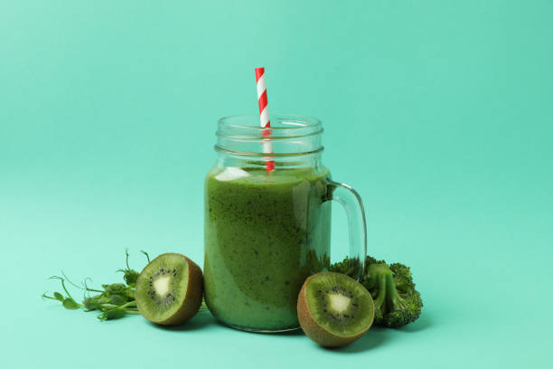 istock Mason jar with green smoothie and ingredients on mint background 1311124006