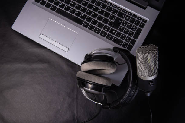 istock home work, professional condenser microphone, headphones and computer on dark surface, top view. 1311124109