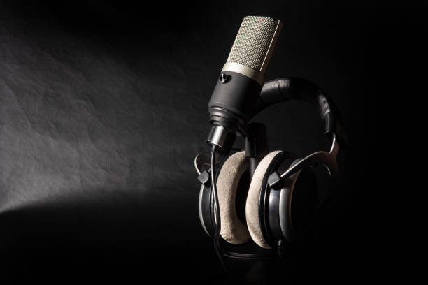 istock professional condenser microphone and headphones on dark surface, low key portrait, dark background, selective focus. 1311124246