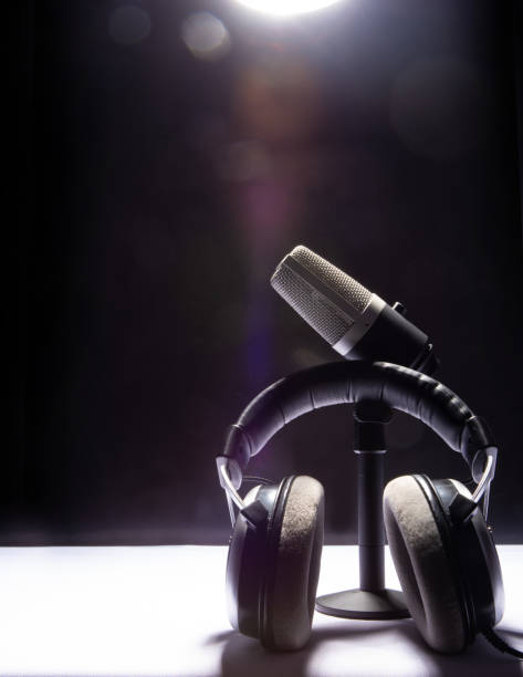 istock professional condenser microphone and headset on white surface and black background, low key portrait, selective focus. 1311124322