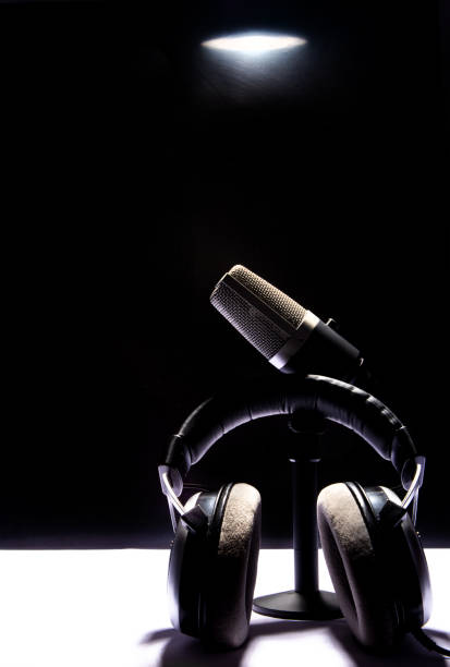 istock professional condenser microphone and headset on white surface and black background, low key portrait, selective focus. 1311124325