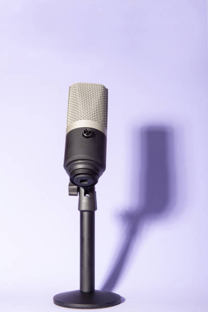 istock professional condenser microphone with pedestal isolated on violet background creating shadow, selective focus. 1311124347