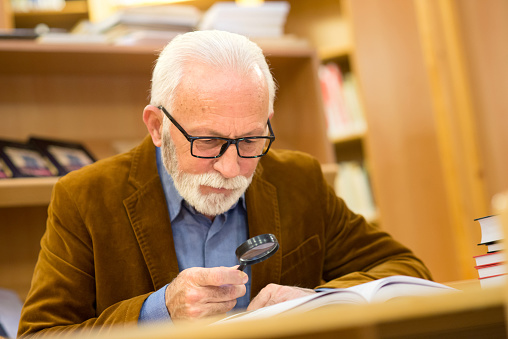 Senior man reading books in the library.