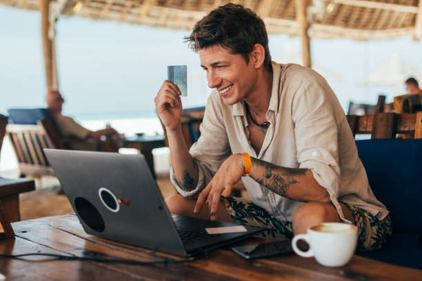 jeune homme payant en ligne avec la carte de crédit au bar de plage - 2274 photos et images de collection