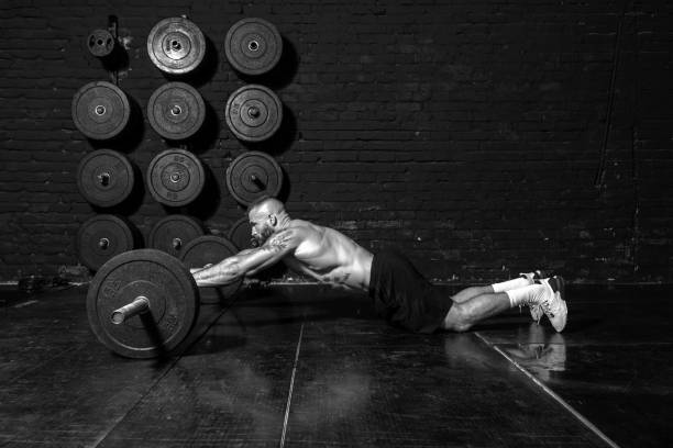 istock Young active strong fit sweaty muscular man with big muscles doing abs workout by rolling barbell weights in the floor of the gym as hardcore cross training real people exercise 1311125441