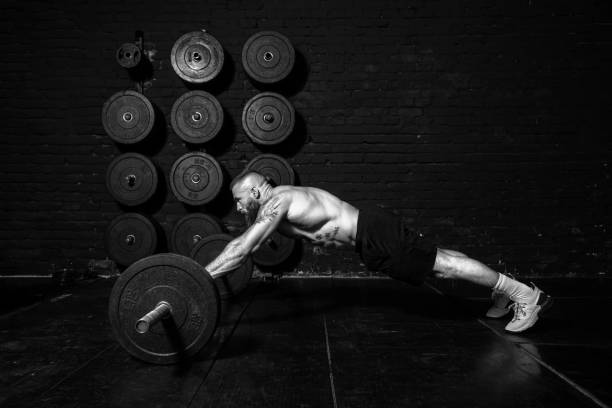 istock Young active strong fit sweaty muscular man with big muscles doing abs workout by rolling barbell weights in the floor of the gym as hardcore cross training real people exercise 1311125446