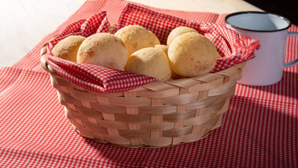 istock Cheese bread, basket lined with red and white fabric filled with cheese bread on a checkered towel and a white cup, selective focus. 1311125611