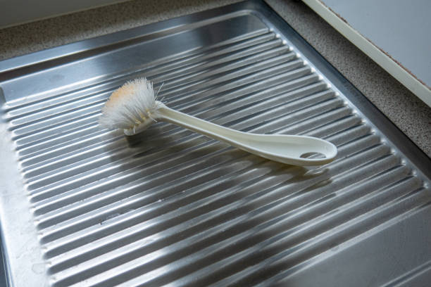 a white dish brush lies on the kitchen sink