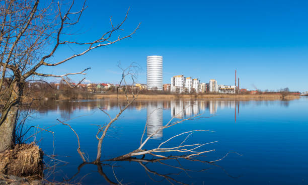 A view over the small Lake Munksjön and Munksjöstaden with the Munksjö tower, in the city of Jönköping, Sweden Public area in the south part of the city of Jönköping; Sweden. Bare tree branches against blue sky and the blue water of Lake Munksjön. Munksjöstaden in the background. jonkoping stock pictures, royalty-free photos & images