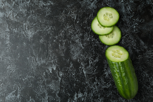 Ripe cucumber and slices on black smoky background