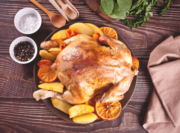 istock Roasted whole chicken with oranges and potatoes on a plate. 1311129132