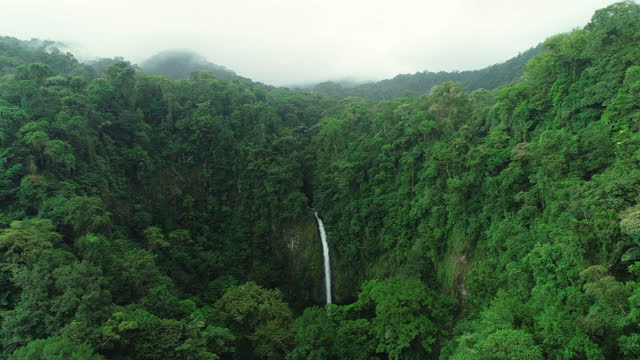 La Fortuna Waterfall in the rainforest near Arenal Volcano in Costa Rica, Central America. Beautiful nature landscape at tourist travel destination landmark. Aerial drone video footage
