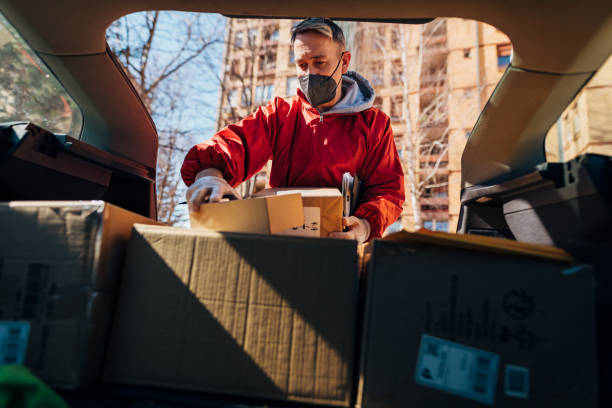 istock Postal worker in the uniform, organising the packages, while looking for the right one so he can deliver the right on to the customer 1311130268