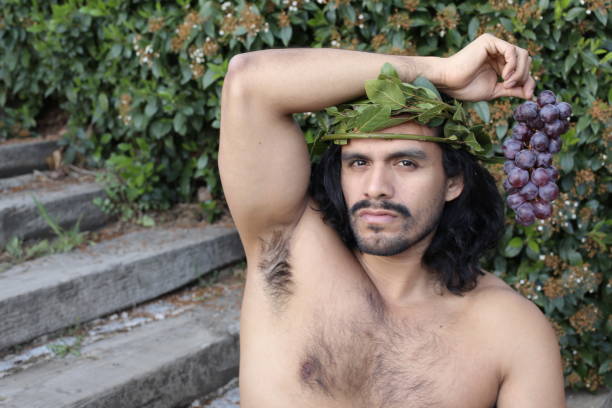 istock Attractive Mediterranean man with laurel crown holding grapes 1311132450