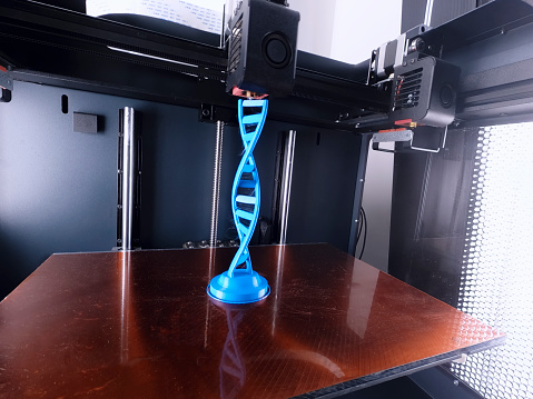 3D printer constructing DNA structure model from blue plastic.