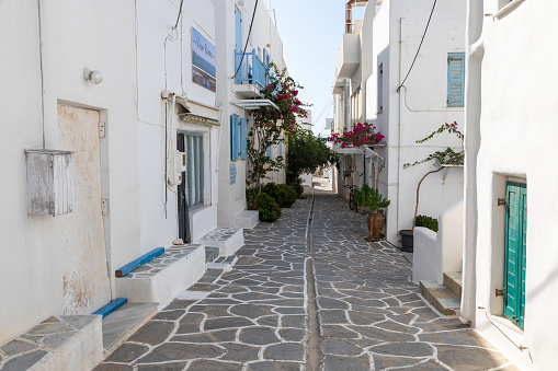 Piso Livadi, Paros Island, Greece - 27 September 2020: Narrow street of the old town with shops and restaurant. Traditional, withe architecture and a stone path with white joints.