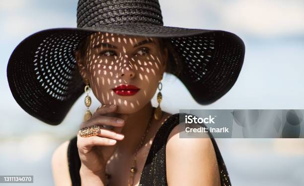 Woman In Hat Portrait Fashion Luxury Model In Black Summer Hat With Make Up And Golden Jewelry Close Up Beauty Face Over Sky Background Stock Photo - Download Image Now
