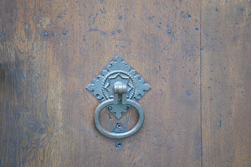 This is a door lock and door knocker on old doors photographed in daylight