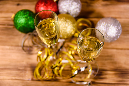 Two wineglasses with champagne and different christmas decorations on rustic wooden table
