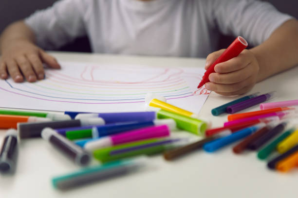 istock boy child sits at home at a table and draws with colored markers on a white sheet 1311138506