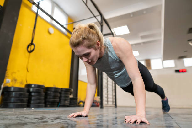 un jeune athlète féminin faisant des pompes dans la gymnastique - athlete push ups muscular build female photos et images de collection