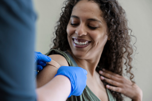 An African American woman gets a vaccination.