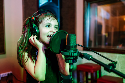 child singer recording song in professional music studio