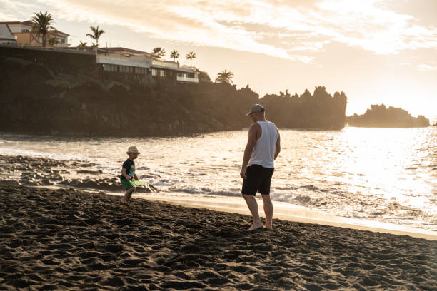 istock Father and son playing on sunset beach. Tropical vacations and father's day concept. 1311142698