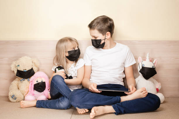 istock Kids wearing face masks using tablet among toys in face masks. 1311143520