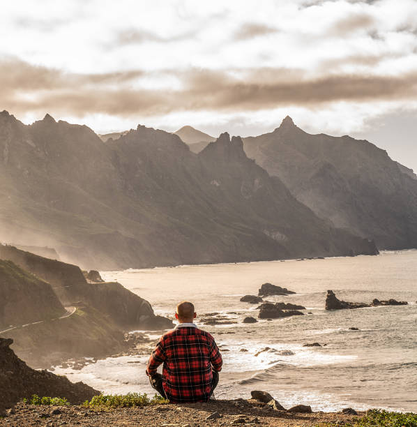 istock One man meditating at sunset, looking at beautiful ocean landscape 1311144804