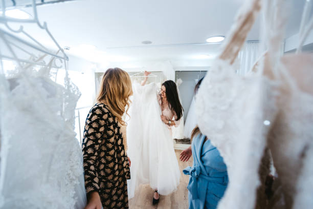 Trying wedding dress Young Caucasian beautiful woman trying wedding dress with her two best friends. wedding dress stock pictures, royalty-free photos & images