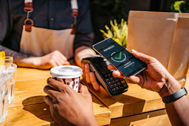 Woman paying via contactless channel by mobile banking application Woman paying via contactless channel by mobile banking application for coffee in coffee shop. Close up. mobile payment stock pictures, royalty-free photos & images