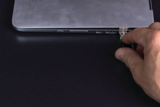 黒い背景に隔離銀のノートブックコンピュータにusbフラッシュドライブを接続する人の手のクローズアップビュー。 - usb flash drive usb cable isolated close up ストックフォトと画像