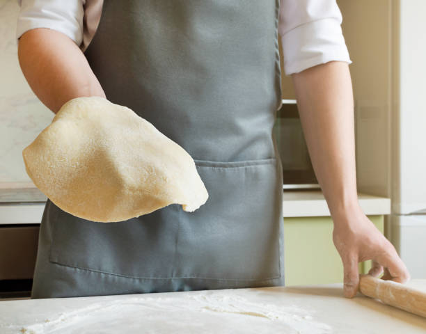 istock chef holds a rolled round dough in his hand 1311147640