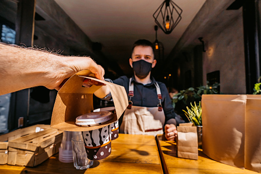 Buying coffee to go in coffee shop from barista