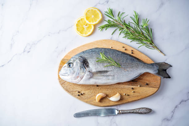 istock Raw fresh dorada fish with lemon slices and greens 1311149120