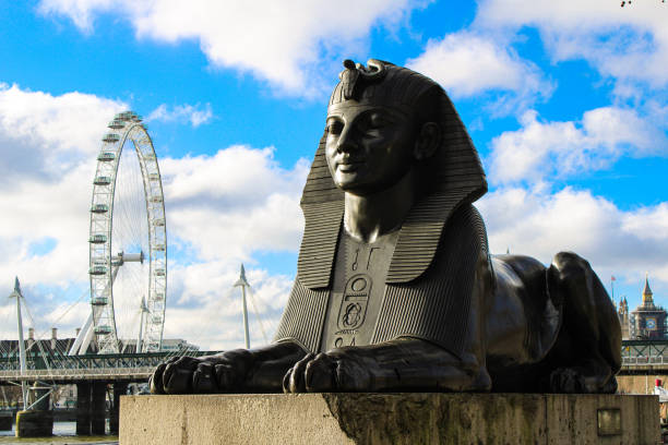 The Sphinx beneath Cleopatra's Needle and the Millenium Wheel on a sunny day in London, 2021