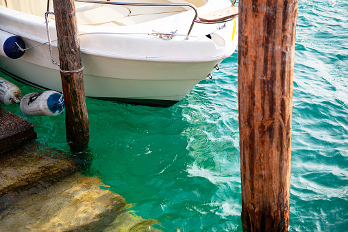 Ship's bow and aquamarine water, lake Garda. Boat and sea, detail. Sailing vessel drops anchor in a quiet bay. Lake Garda, Sirmione del Garda, Italy, Europe. Peaceful place