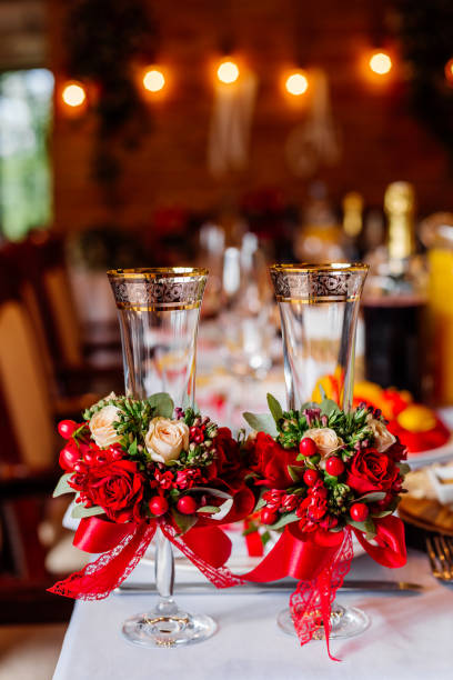 istock Two empty wedding glasses, decorated with greenery, red roses and ribbon, standing  on the banquet table. 1311152033