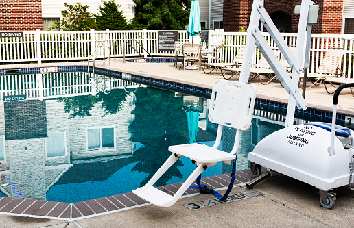 An outdoor pool in the courtyard of an hotel has a handicapped lift for people who use wheelchairs.