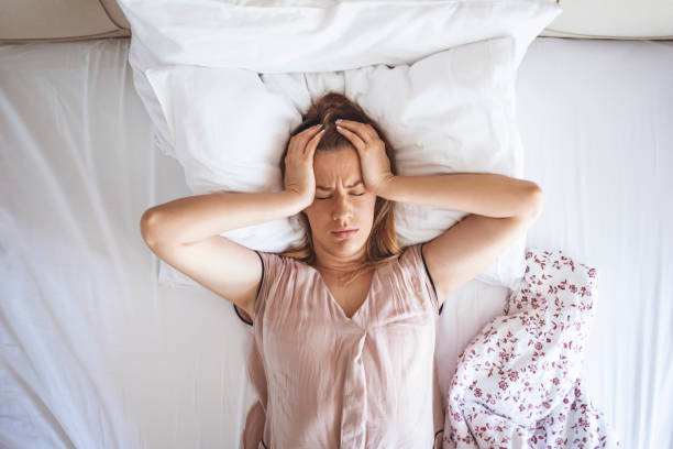 Desperate girl suffering insomnia trying to sleep Desperate girl suffering insomnia trying to sleep. Young woman distressed. One woman trying to sleep covering her ears to avoid neighbour noise at home or hotel during the day. inconvenience photos stock pictures, royalty-free photos & images