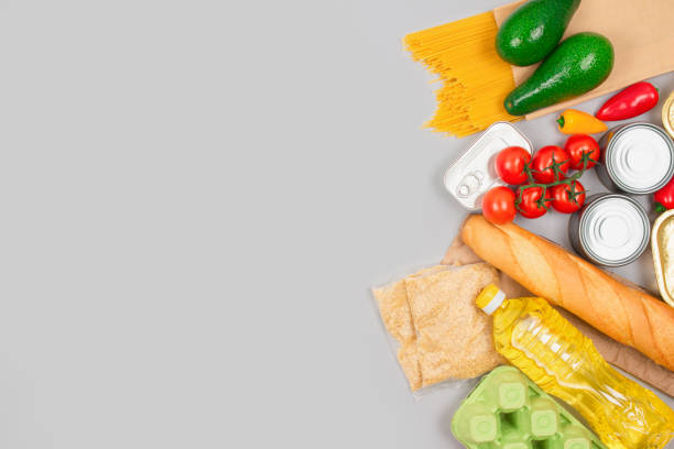 istock Flat lay composition with food donations on light gray background with copy space - pasta, fresh vegatables, canned food, baguette, cooking oil. Food donation and food bank concept. Selective focus 1311156244