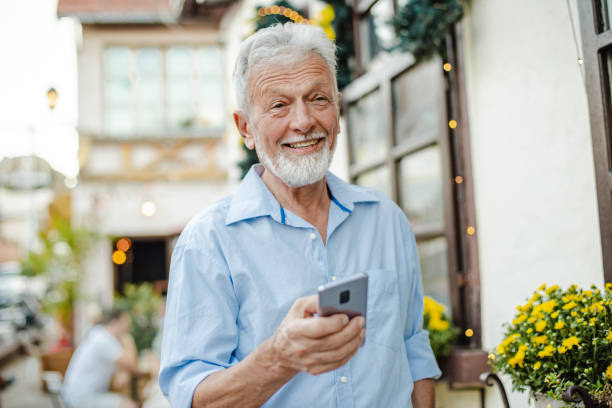istock Happy senior man is using mobile phone on the street 1311157264