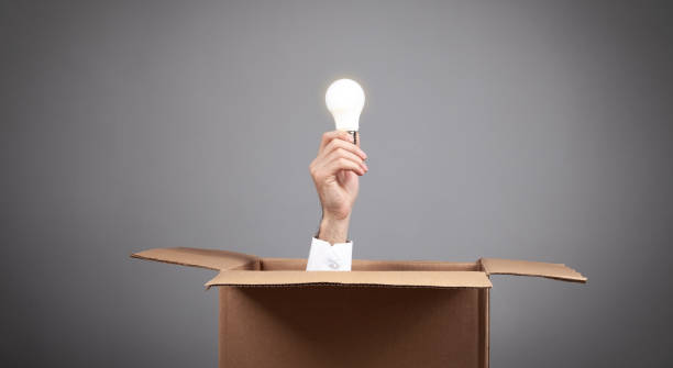 istock Male hand holding a light bulb coming out from a cardboard box. 1311159227