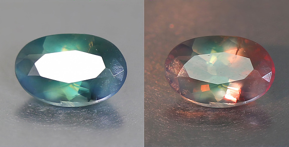 Natural gemstone alexandrite with color change on gray background