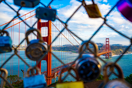 Golden Gate Bridge at sunset photographed through love locked chain linked fence