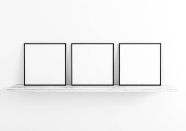 istock Triple 10x10 Square Black Frame mockup on white wooden shelf and white wall. 1311164459